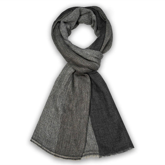A dark gray and black herringbone patterned scarf, styled in a loop with one end hanging down, set against a plain white background.