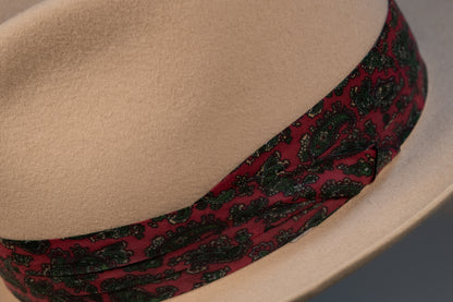 Close-up of a bone white rabbit fur fedora with a red and green paisley patterned band.