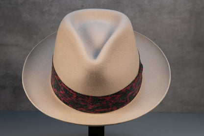 A bone white rabbit fur fedora hat with a decorative band on a stand against a neutral background.