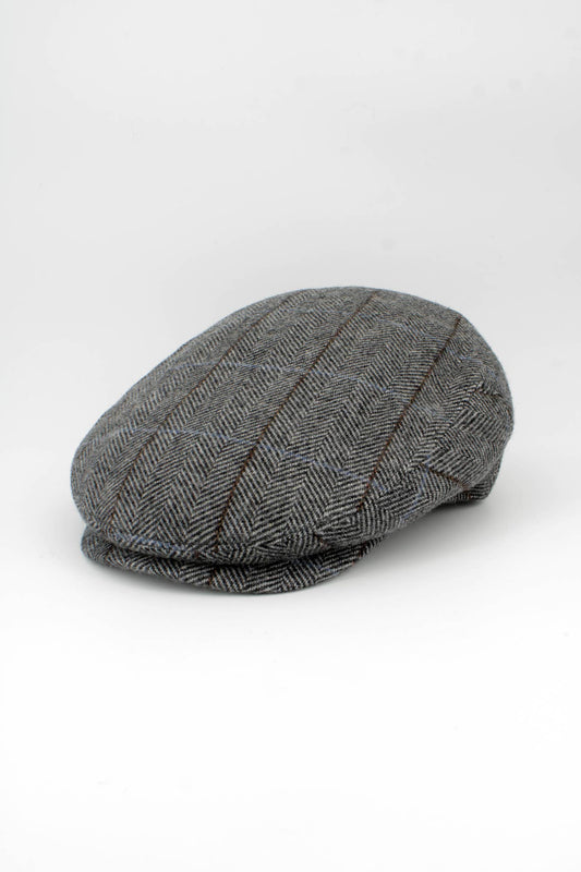 A classic flat cap in a gray and black herringbone pattern with subtle brown stripes, photographed on a seamless white studio background.
